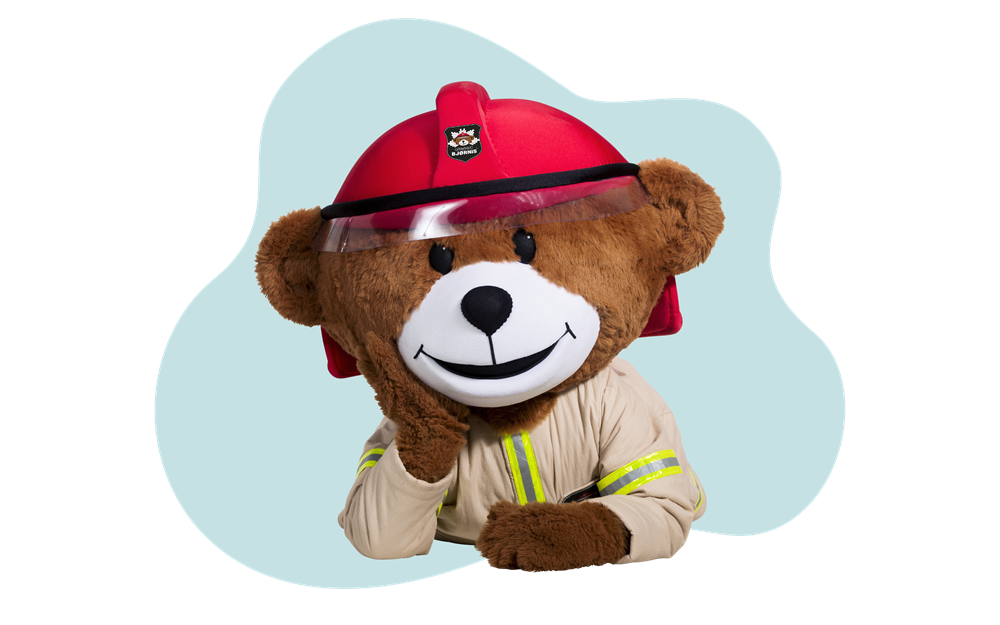 Bamsefigur kledd som brannkonstabel med hjelm og verneutstyr.